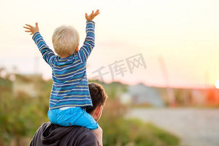 父亲孩子摄影照片_快乐的男人和他的孩子在户外玩耍。家庭生活方式，夕阳下父子俩的田园风光。