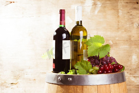橡木桶上的一瓶瓶葡萄酒覆盖着破旧的木质背景。几瓶葡萄酒