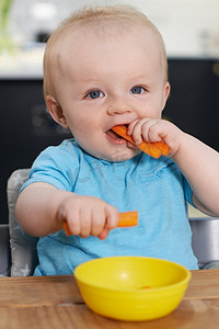 愉快的幼儿坐在吃新鲜的胡萝卜表
