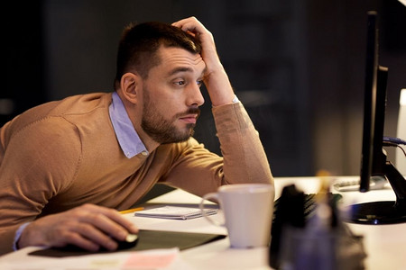 商务、超负荷工作、截止日期和人的概念--疲惫的男人在夜间办公室的餐桌上。疲惫的男人在夜间办公室的餐桌上