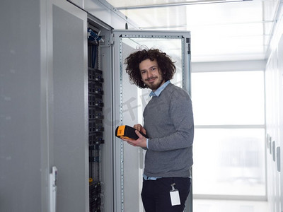 年轻的IT技术人员在大型数据中心的服务器上使用数字电缆分析仪