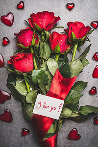 大花束，红玫瑰，彩带，我爱你字样卡片和心形在灰色背景上，俯视