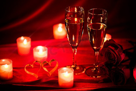 香槟和蜡烛。情人节庆祝活动，红丝绸上的香槟、蜡烛、玫瑰和红心
