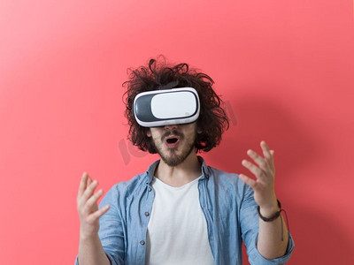 快乐男士使用虚拟现实的VR耳机眼镜获得体验，红色背景下孤立