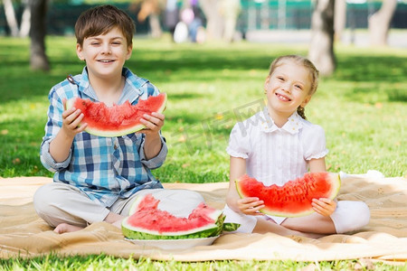 孩子们吃摄影照片_孩子们吃西瓜。公园里的可爱小朋友吃着多汁的西瓜