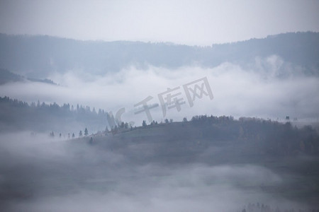 秋天的山雨和雾气。晨雾笼罩着山丘和森林。山顶周围有浓雾。秋季背景
