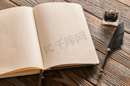 羽毛笔和空白笔记本页，木质背景