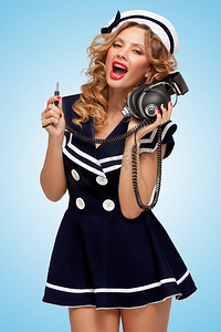 音乐宣传背景摄影照片_一张时尚的水手女孩的复古照片，蓝色背景下戴着大的复古音乐耳机。