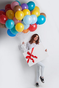 拿着气球和礼物的女人。带着气球和大礼盒的微笑的年轻女子