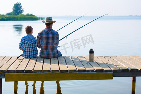 男孩和他的父亲一起钓鱼。一个男孩和他的父亲一起在码头钓鱼