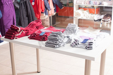 成行堆放在服装店白色货架上的红色裤子。新潮服装店