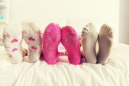 友谊、人和睡衣派对的概念--家里床上穿着袜子的女人的特写。家里床上穿着袜子的女人的特写