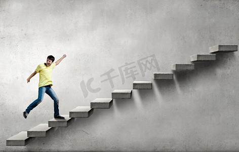 年轻的商人走上楼梯，代表成功的概念。在职业阶梯上往上爬