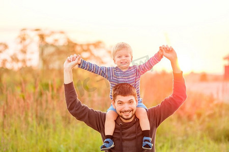 日照摄影照片_快乐的男人和他的孩子在户外玩耍。家庭生活方式，夕阳下父子俩的田园风光。