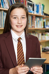 在图书馆使用数字平板电脑拍摄的穿着校服的女孩肖像