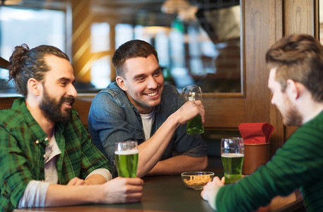 色绿摄影照片_人，休闲和圣帕特里克节的概念-快乐的男性朋友在酒吧或酒吧喝绿啤酒。在酒吧或酒吧喝绿啤酒的男性朋友
