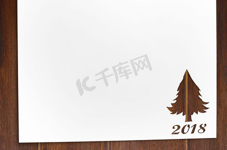 在桌子上切成冷杉树形状的纸。在木桌上剪下冷杉树形状的纸，作为2018年圣诞卡或新年背景
