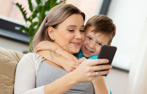家庭、技术和人的概念-快乐的母亲和小儿子在家中有智能手机。家里有智能手机，幸福的家庭