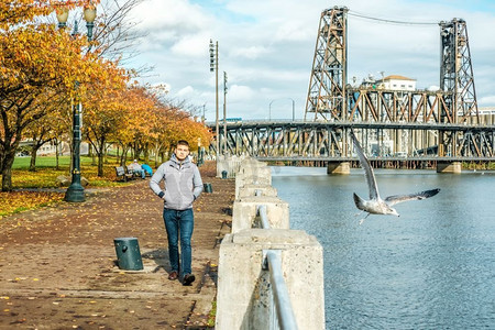 秋天，美国俄勒冈州波特兰市，一名男子在河边散步。