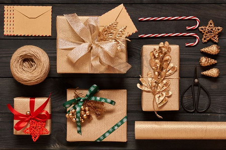 创意包装和装饰的圣诞礼物在黑色木制背景的盒子里。从上面俯瞰。平躺着。