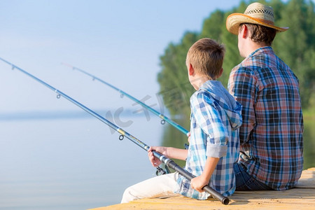 男孩和他的父亲一起钓鱼。男孩和他的父亲一起在码头钓鱼