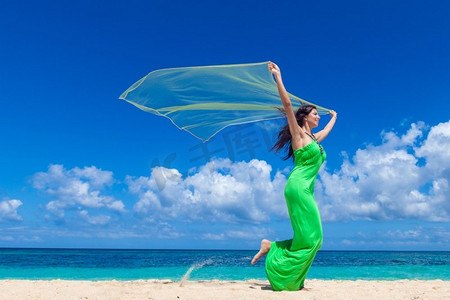 海滩奔跑的美摄影照片_海滩上穿着布料的女人。年轻美人手持布料在海滩上奔跑
