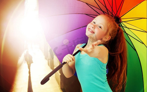 开朗的红发女孩撑着一把五颜六色的伞