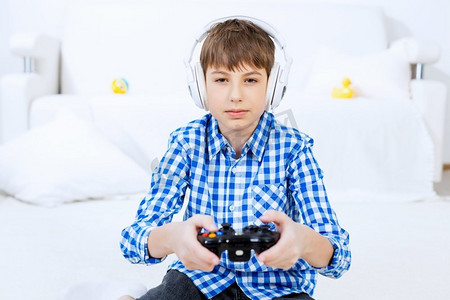 玩游戏机的男孩。情绪激动的男孩坐在地板上玩操纵杆游戏