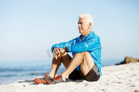 穿着运动服的男人坐在海滩上。穿着运动服的男人独自坐在海滩上休息一分钟