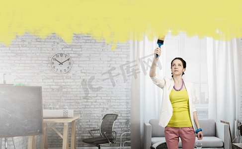 家居和房屋翻新混合媒体。在翻新的室内用油漆滚筒或画笔的女人