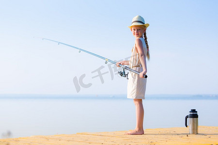 女孩在一条裙子和一顶帽子与钓鱼竿。女孩在一件衣服和一顶帽子与钓鱼竿钓鱼从码头