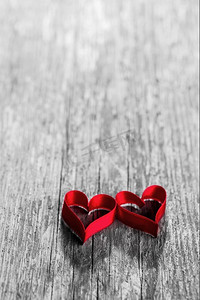 木质背景上的两个红丝带心形，情人节概念