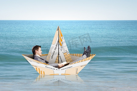 坐在纸做的船上的商人。成功的商人在金融海洋中的纸船上航行