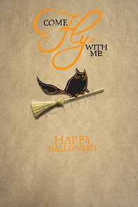 万圣节创意概念照片，一只猫骑在棕色背景纸做的扫帚上。