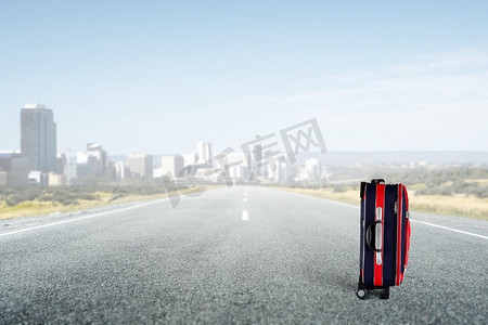 红色行李箱在路上。红色行李箱上路的旅行理念
