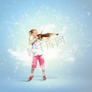 小提琴中提琴摄影照片_拉小提琴的女孩。在蓝色背景下拉小提琴的可爱女孩形象