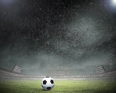 大气欧式摄影照片_足球。倾盆大雨落在球场上，足球落在草地上