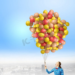 拿着气球的女人。穿着休闲衣服的年轻女子手里拿着一堆彩色气球