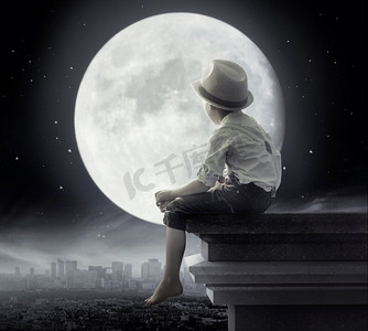 黑白月亮摄影照片_黑白图片的一个可爱的男孩坐在屋顶上