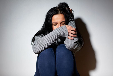 人,悲伤和家庭暴力的概念-不快乐的女人坐在地板上哭泣.