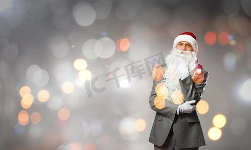 商业圣诞老人。戴着圣诞老人帽子，手托着下巴的体贴的商人
