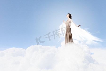 天使女孩飞得很高。天空背景下长着天使翅膀的迷人女子