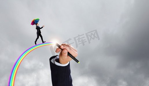 在创造力的浪潮中。撑着伞的商人走在高空的彩虹上