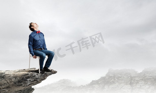 男人在上面。情绪激动的商人坐在山顶的椅子上