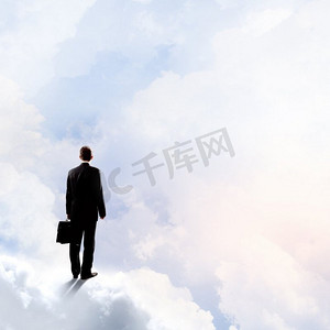 生意兴隆。商人站在高空的云上的背影