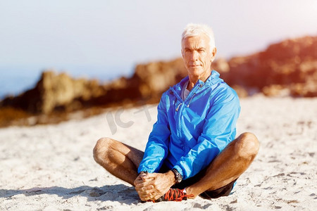 穿着运动服的男人坐在海滩上。穿着运动服的男人独自坐在海滩上休息一分钟