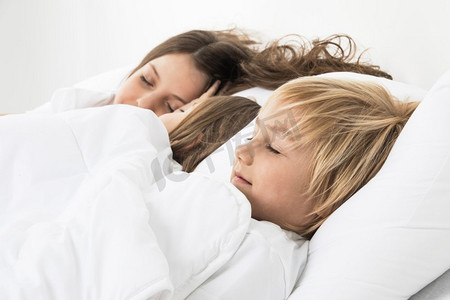 睡觉男孩摄影照片_三个孩子睡在床上。三个漂亮的孩子睡在一张白色的毯子下