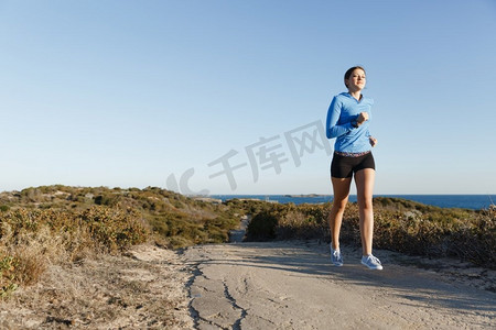 健身模型摄影照片_体育跑步者慢跑在海滩锻炼出来。适合女性健身模型慢跑沿海洋