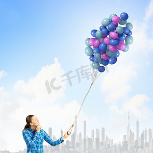 免费建党节摄影照片_拿着气球的女人。穿着休闲衣服的年轻女子手里拿着一堆彩色气球