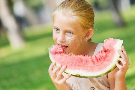 吃西瓜的女孩。可爱的女孩在公园吃多汁的西瓜